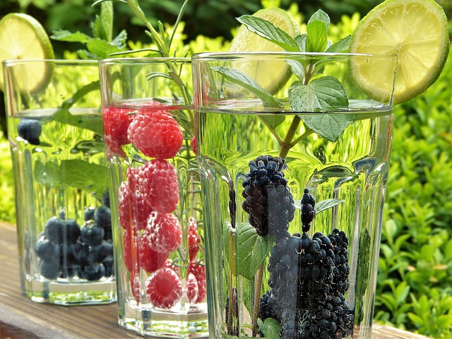 friss nyári gyümölcsök vizzel teli poharakban